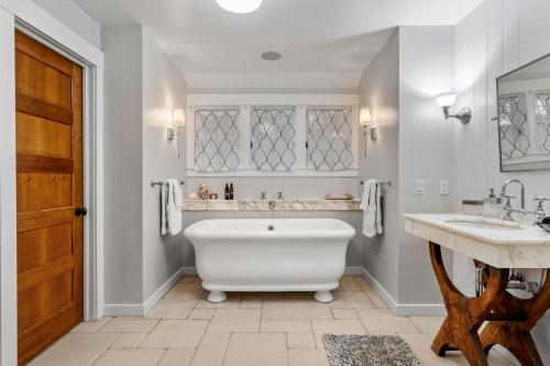 明尼阿波利斯Design House at Linden Hills的一间带白色浴缸、两个水槽和木门的浴室
