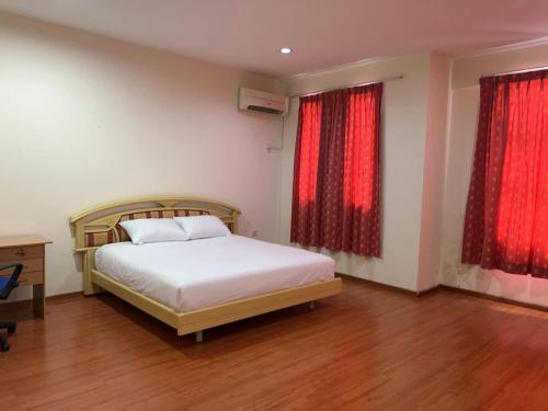 民都鲁1717 Bintulu Homestay 1的一间卧室配有床和两个带红色窗帘的窗户。