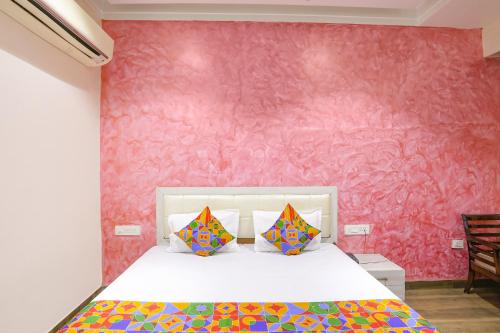 坎普尔FabHotel Uday Villa的一间卧室配有一张粉红色墙壁的床