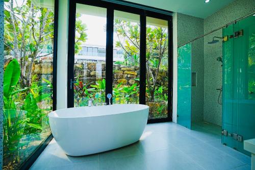富国Kiwuki Beachfront Villa的带浴缸和玻璃淋浴间的大浴室