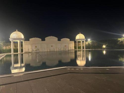 勒克瑙Celestial Chic Suite With Swimming Pool的一座晚上在水中有两个圆顶的建筑