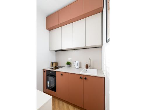 华沙ECRU Design Apartment in City Center WWA46的厨房配有棕色和白色的橱柜和水槽