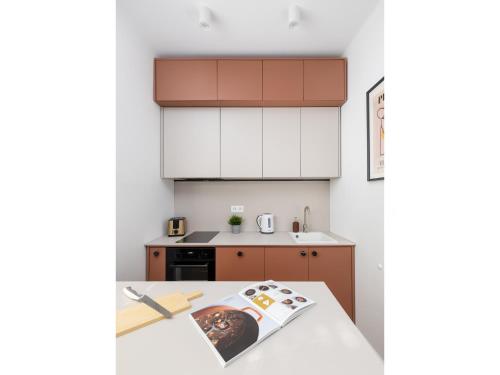 华沙ECRU Design Apartment in City Center WWA46的厨房配有白色橱柜和一张带杂志的桌子