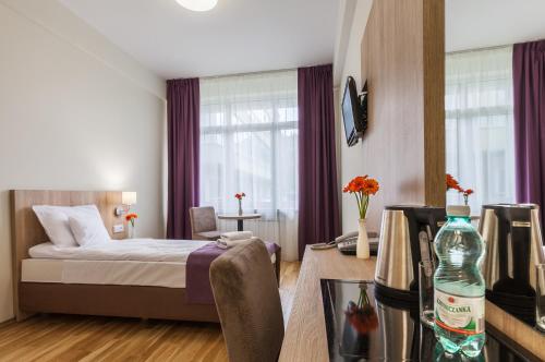 克雷尼察Silesia Krynica的一间卧室配有一张床和一张桌子及一瓶水