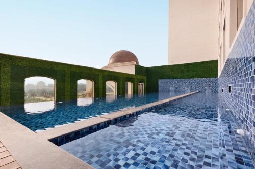 勒克瑙Ramada by Wyndham Lucknow Hotel and Convention Center的蓝色瓷砖建筑中的游泳池