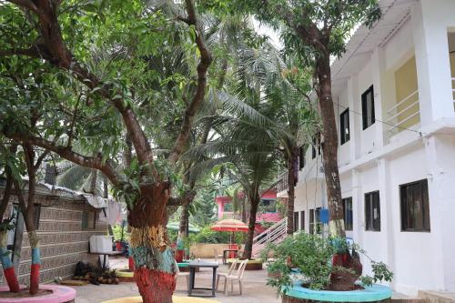 孟买Vellankani Resort Gorai的庭院里种有树木,配有桌椅