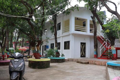 孟买Vellankani Resort Gorai的停在白色建筑前的摩托车