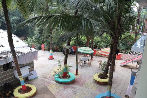 孟买Vellankani Resort Gorai的一个带棕榈树和桌椅的庭院