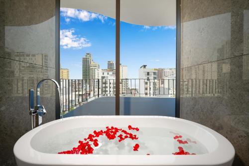 岘港Golden Lotus Grand的浴室配有装满红花的浴缸。