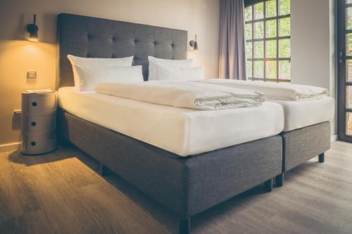 科隆rugs HOTEL Köln的一间卧室配有一张带白色床单的大床