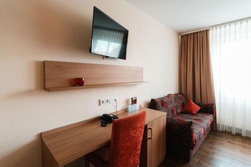 维森布伦施瓦泽尔阿德勒兰德酒店的酒店客房设有一张桌子、一台电视和一张沙发。