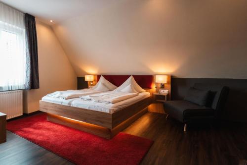 维森布伦施瓦泽尔阿德勒兰德酒店的一间卧室配有一张大床和一把椅子