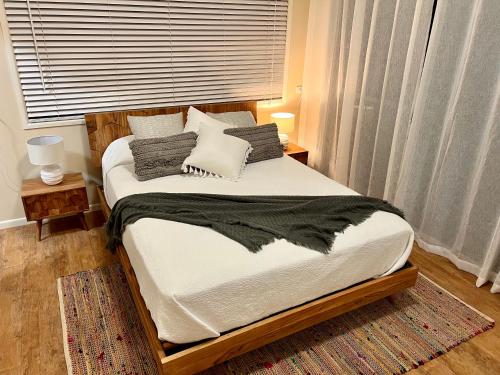 彩虹海滩Tranquil holiday home on the water’s edge.的一间卧室配有带白色床单和枕头的床。