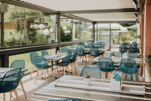 翁肯Dorfcafe Unken Hotelpension sWirtshaus im Dorf的餐厅设有蓝色的椅子和桌子以及窗户。