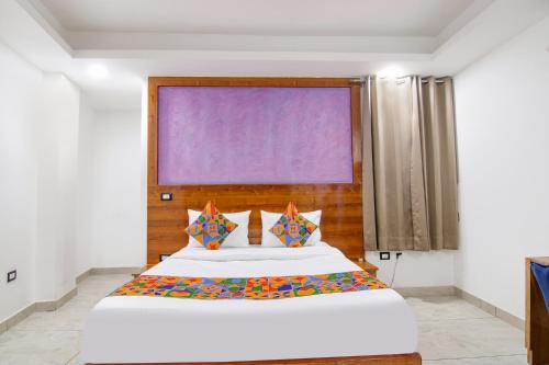 古尔冈FabHotel Garden View的卧室配有一张带彩色枕头的大型白色床。