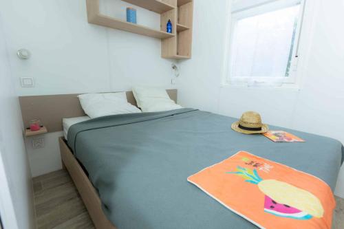 安格雷Camping Bela Basque - Maeva的一间卧室,配有一张床,上面有帽子