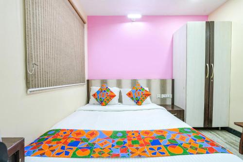 钦奈FabExpress Raj Supreme Residency的一间卧室配有一张带彩色毯子的床