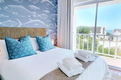 圣赫勒拿湾House Khasia- on the Golden Mile的卧室配有白色床、蓝色枕头和窗户
