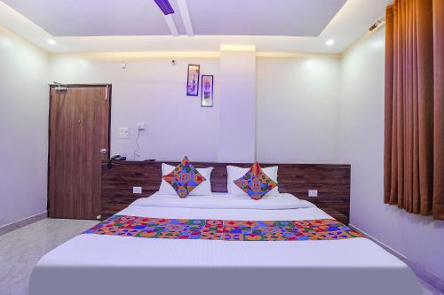 瓦拉纳西FabHotel Nandini Grand的卧室配有一张带彩色枕头的大型白色床。