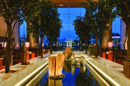 钦奈钦奈凯悦王朝酒店的一座树木繁茂的建筑中间的喷泉
