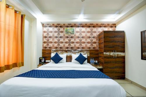 新德里Grand Empire Suites By Delhi Airport的卧室配有带蓝色枕头的大型白色床