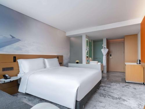 花都Novotel Guangzhou Baiyun Airport的一间带白色大床的卧室和一间浴室