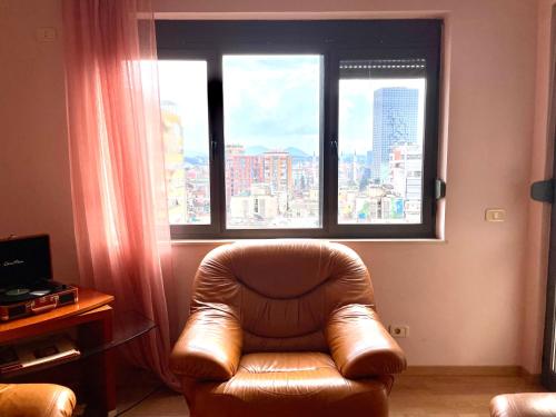 地拉那Easy Peasy - 9th floor view downtown的配有大窗户的客房内的皮椅