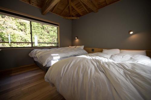 下田横川温泉湯殿ととのゆ的带大窗户的客房内的两张床
