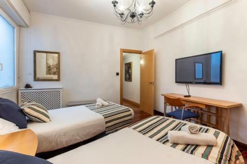 毕尔巴鄂San Mames Apartment - Free Parking的配有书桌和电视的客房内的两张床
