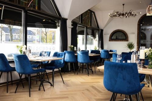 新芬讷普迪茹德雅格酒店的餐厅设有蓝色的椅子和桌子以及窗户。