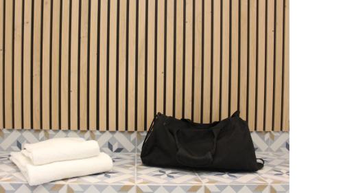 普瓦捷Logis Hôtel de l'Europe的黑色包,坐在地板上,带毛巾