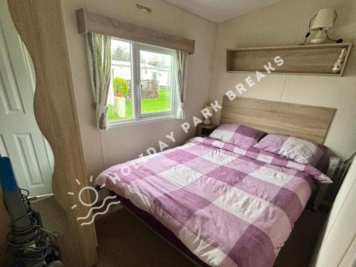 塞尔西Cosy 2 bed @ Seal Bay, Selsey的卧室配有带窗户的紫色和白色床