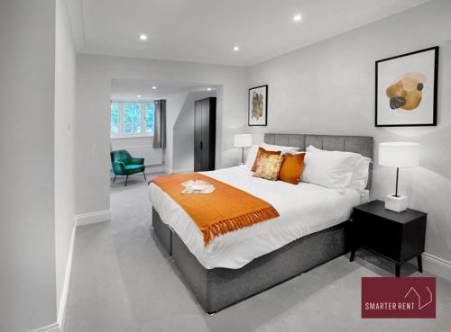 泰晤士迪顿Thames Ditton - Luxury 4 Bedroom House - Garden and Parking的一间卧室配有一张带橙色毯子的大床
