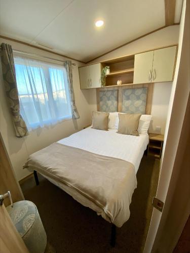 塞尔西Downtime, West Sands, Seal Bay Resort, Selsey的卧室配有一张大白色床和窗户