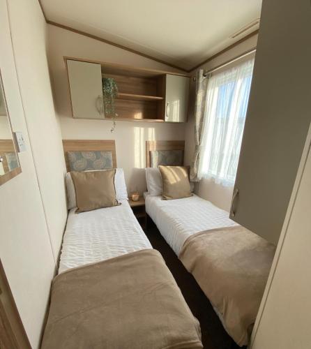 塞尔西Downtime, West Sands, Seal Bay Resort, Selsey的小房间设有两张床和窗户