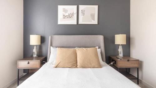 欧文Landing Modern Apartment with Amazing Amenities (ID9245X93)的一间卧室配有一张带两张桌子和两盏灯的床。