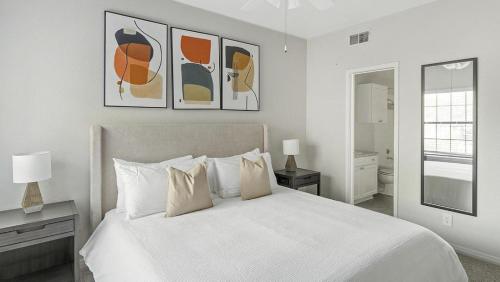 欧文Landing Modern Apartment with Amazing Amenities (ID1242X397)的白色卧室设有一张大床,墙上挂有绘画作品