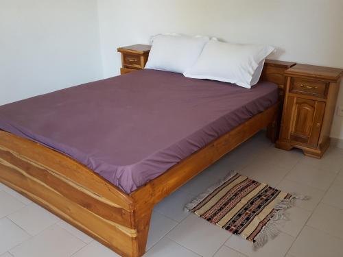 Boukot OuolofMaison Yaka的一张带木制床架和床头柜的床