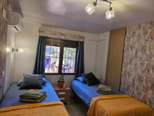 卡尔佩Casa Veintiuno en Calp的一间卧室设有两张床和窗户。