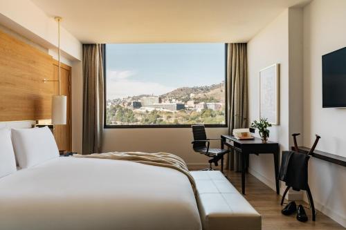 巴塞罗那Torre Melina, a Gran Meliá Hotel的配有一张床、一张书桌和一扇窗户的酒店客房