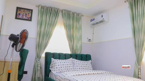 拉各斯Richard Magodo Apartment的一间卧室设有一张绿色的床和一个窗户。