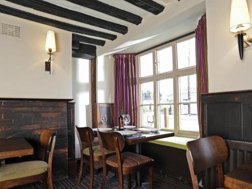 剑桥红狮酒店的一间带桌椅和窗户的用餐室