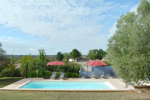 RoumagneMaison à 6 km de Eymet piscine chauffée.的一个带两把遮阳伞和椅子的游泳池