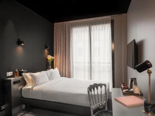 巴黎Grand Hotel Lafayette的一间卧室配有一张床、一张书桌和一个窗户。