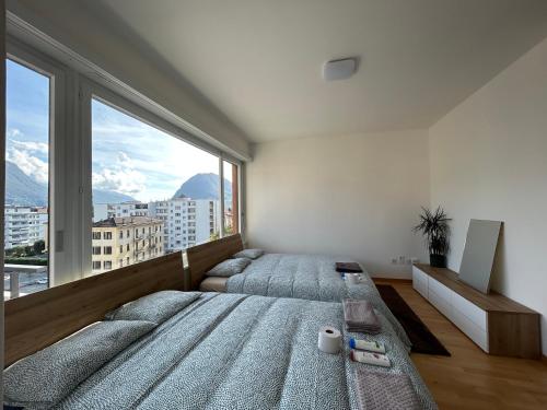 卢加诺Switzerland Apartment Lugano central location的一间卧室设有两张床和大窗户