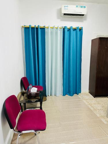 沙迦Room for rent的一间设有两把椅子和一张桌子的房间,以及蓝色的窗帘