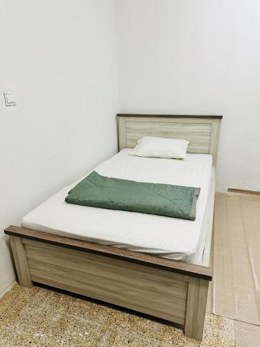 沙迦Room for rent的一张铺有白色床单和木架的床