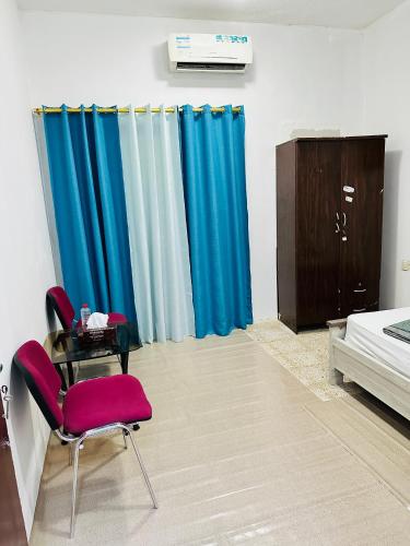 沙迦Room for rent的一间卧室配有蓝色窗帘、桌子和床