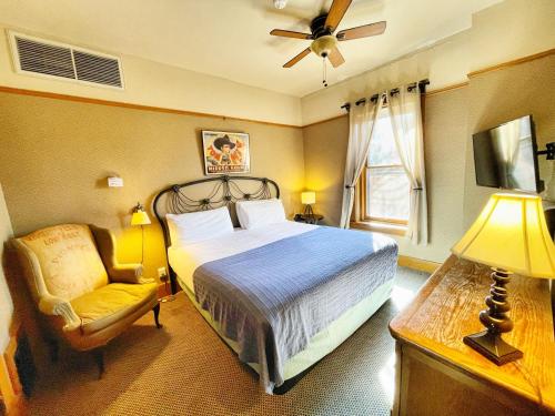 普雷斯科特旺多姆酒店的一间卧室配有一张床、一把椅子和风扇