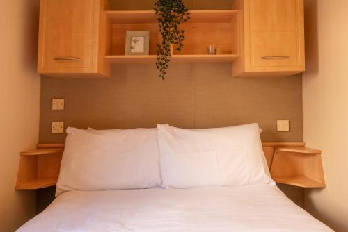 巴恩斯特珀尔No1 Meadow Brook的卧室配有白色的床铺和木柜